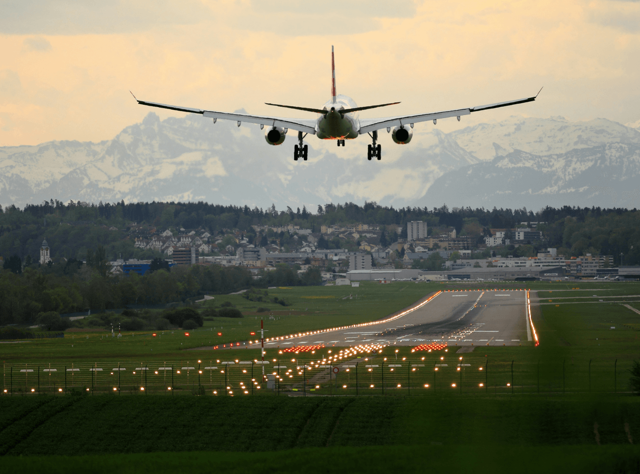 aeroplane descending onto a runway with buildings in the background